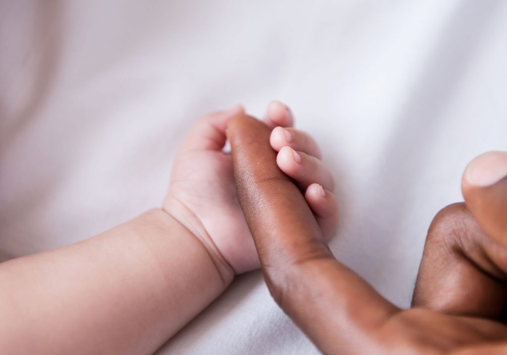 Close-up of little baby holding fathers finger