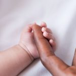 Close-up of little baby holding fathers finger